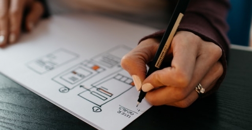 Person drawing wireframes and writing the words "user goalds"