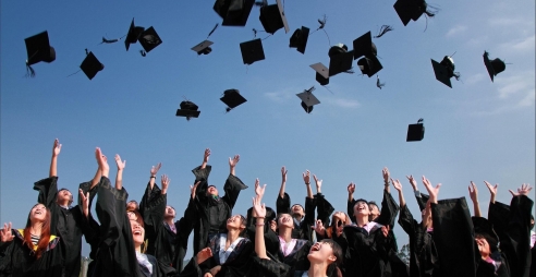Group of graduating students throwing their caps into the air