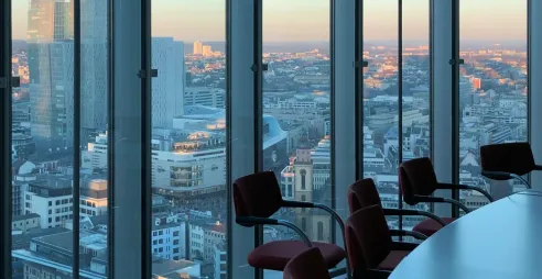 A boardroom with large glass windows and a dusky view of a city.