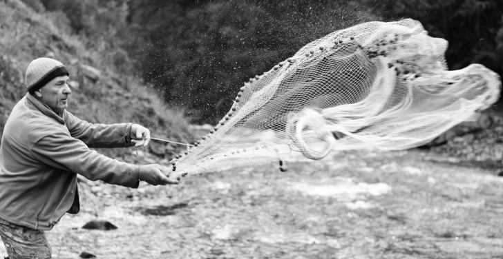 A fisherman casts a net into a Georgian river.