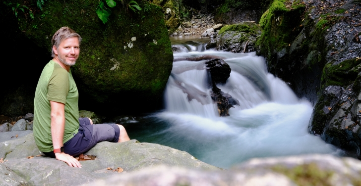 Petr Illek takes a rest on a rock above a river during a hike.