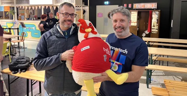 Adrien Sirjacques and Tony Barker pose proudly with DrupalCon Lille mascot Lil’ Rooster.