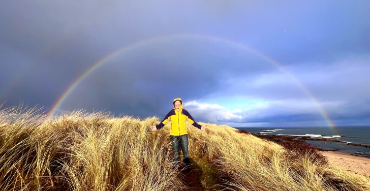 Tony Barker out on a hike. In the background is a rainbow.