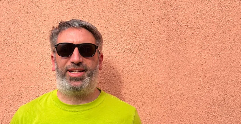 Tony Barker, in sunglasses and a lime T-shirt, against the backdrop of a peach-coloured wall.