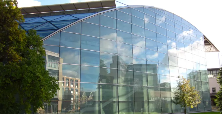 Cambridge University's buildings are reflected in the glass exterior of its modern law building.