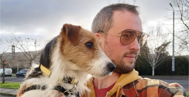 Luke Brennan holds Buddy, his dog, while they take a selfie, looking to the right.