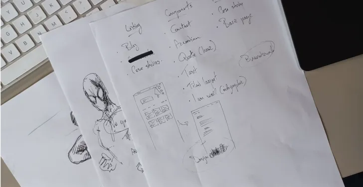 Sheets of papers containing notes and doodles lie on top of a white keyboard.
