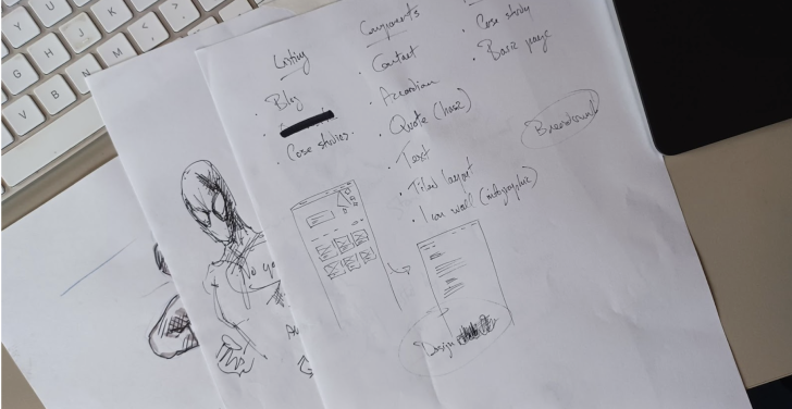 Sheets of papers containing notes and doodles lie on top of a white keyboard.