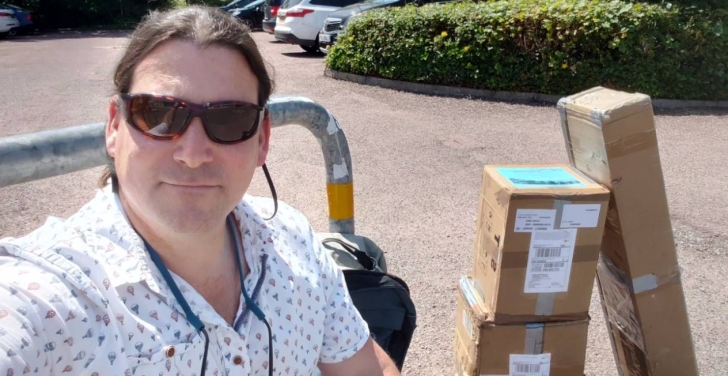 Annertech's Simon White takes a selfie with three boxes filled with banners and swag.