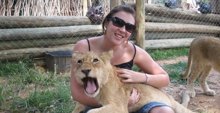 A lion cub yawns as it lies on Ilana lap.