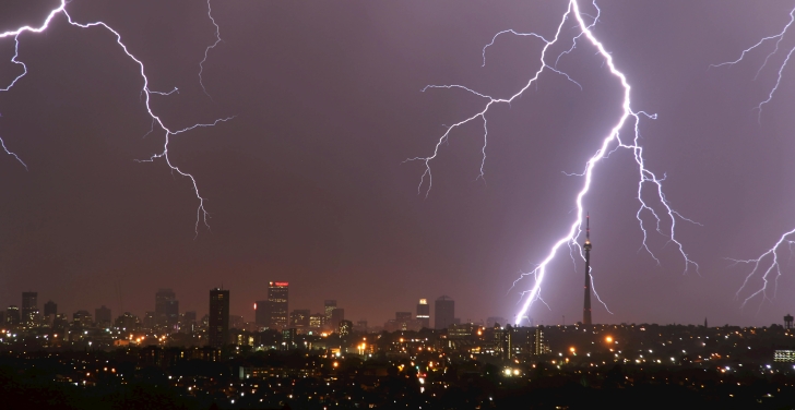 Huge flashes of lightning streak across the sky, over a cityscape of Johannesburg.
