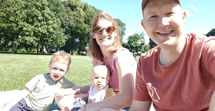 A family of four take a selfie while enjoying a picnic in the sun