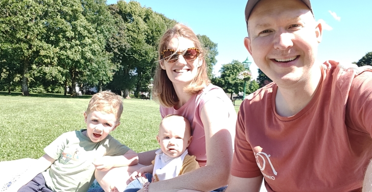A family of four take a selfie while enjoying a picnic in the sun