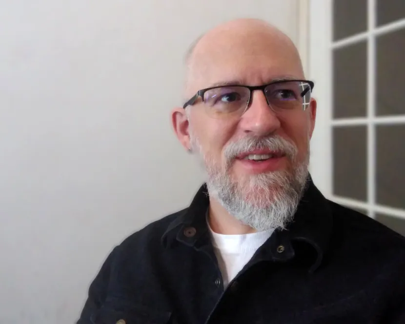 A headshot of Christopher Torgalson. He is wearing black spectacles and is standing next to a window.