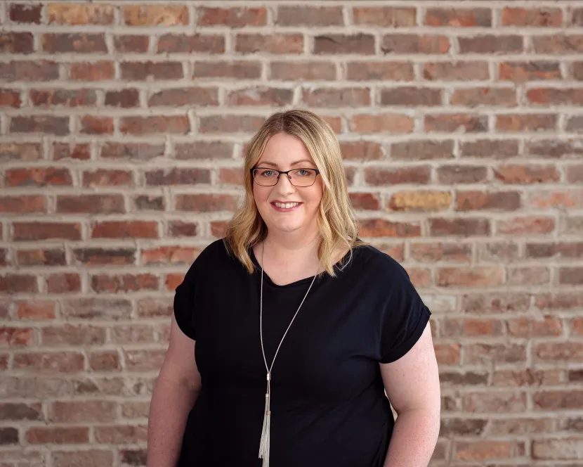 Stella Power is standing in front of a brick wall.