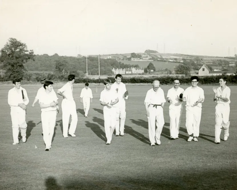 An old, black and white image of men coming off a cricket pitch