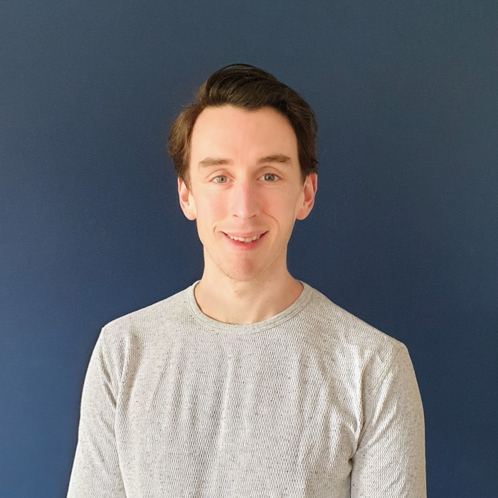 Gavin Hughes stands against a dark blue background.