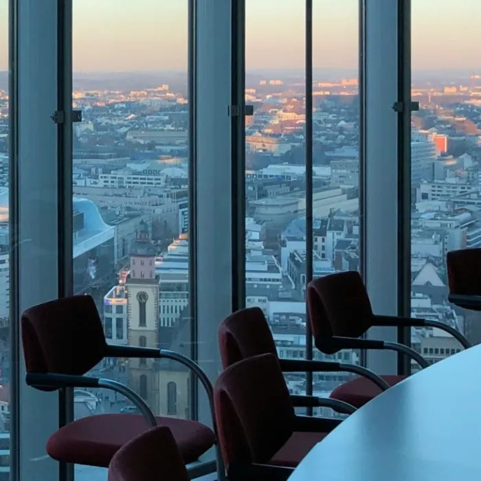A boardroom with large glass windows and a dusky view of a city.
