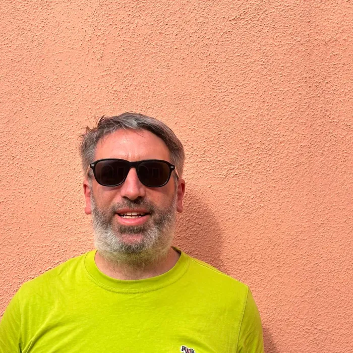 Tony Barker, in sunglasses and a lime T-shirt, against the backdrop of a peach-coloured wall.