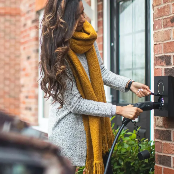 A woman plugs in the charging cable for her electric vehicle.