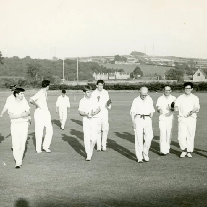 An old, black and white image of men coming off a cricket pitch