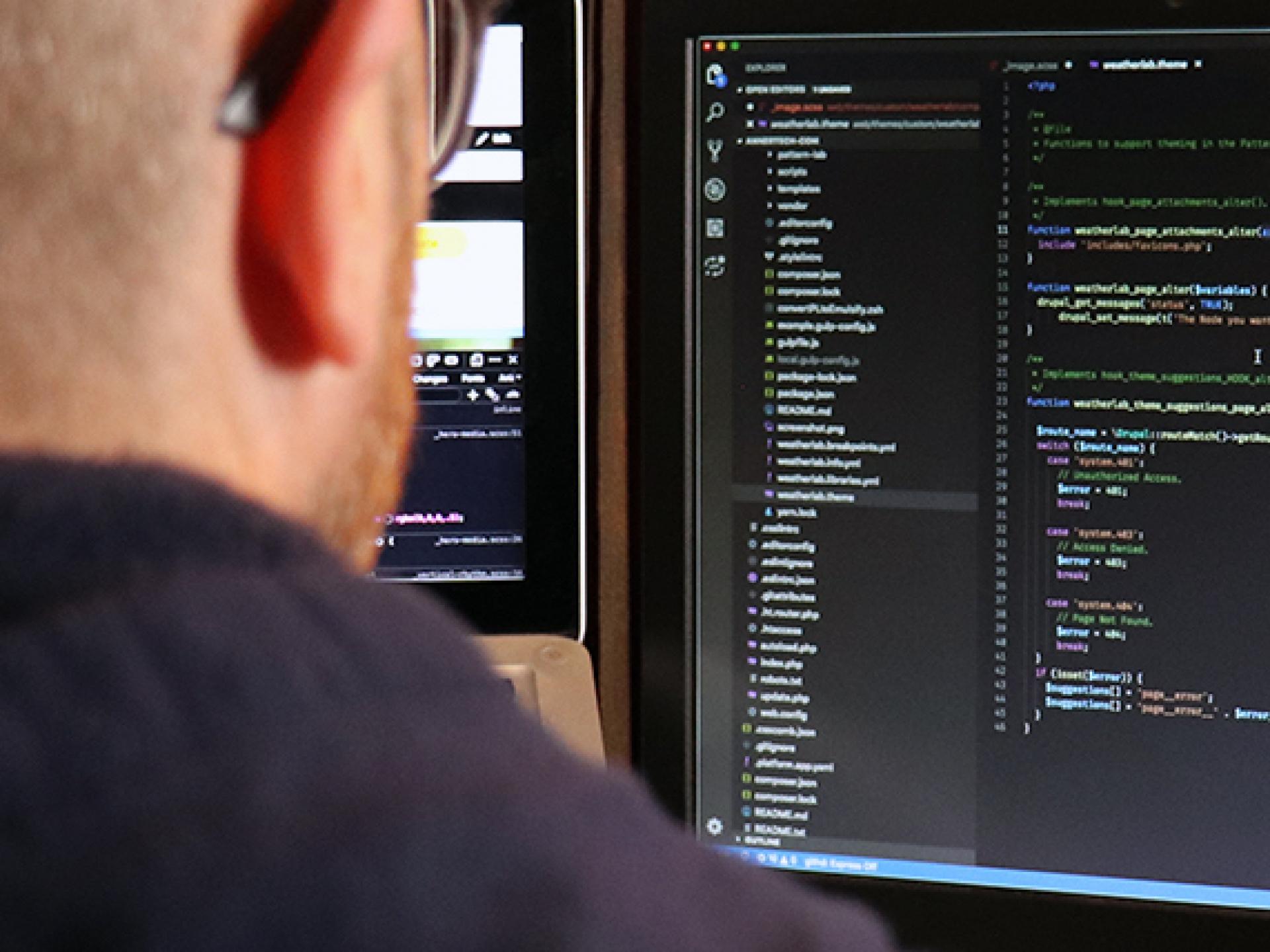 Man sitting at computer with code on the screen | Annertech Development Services