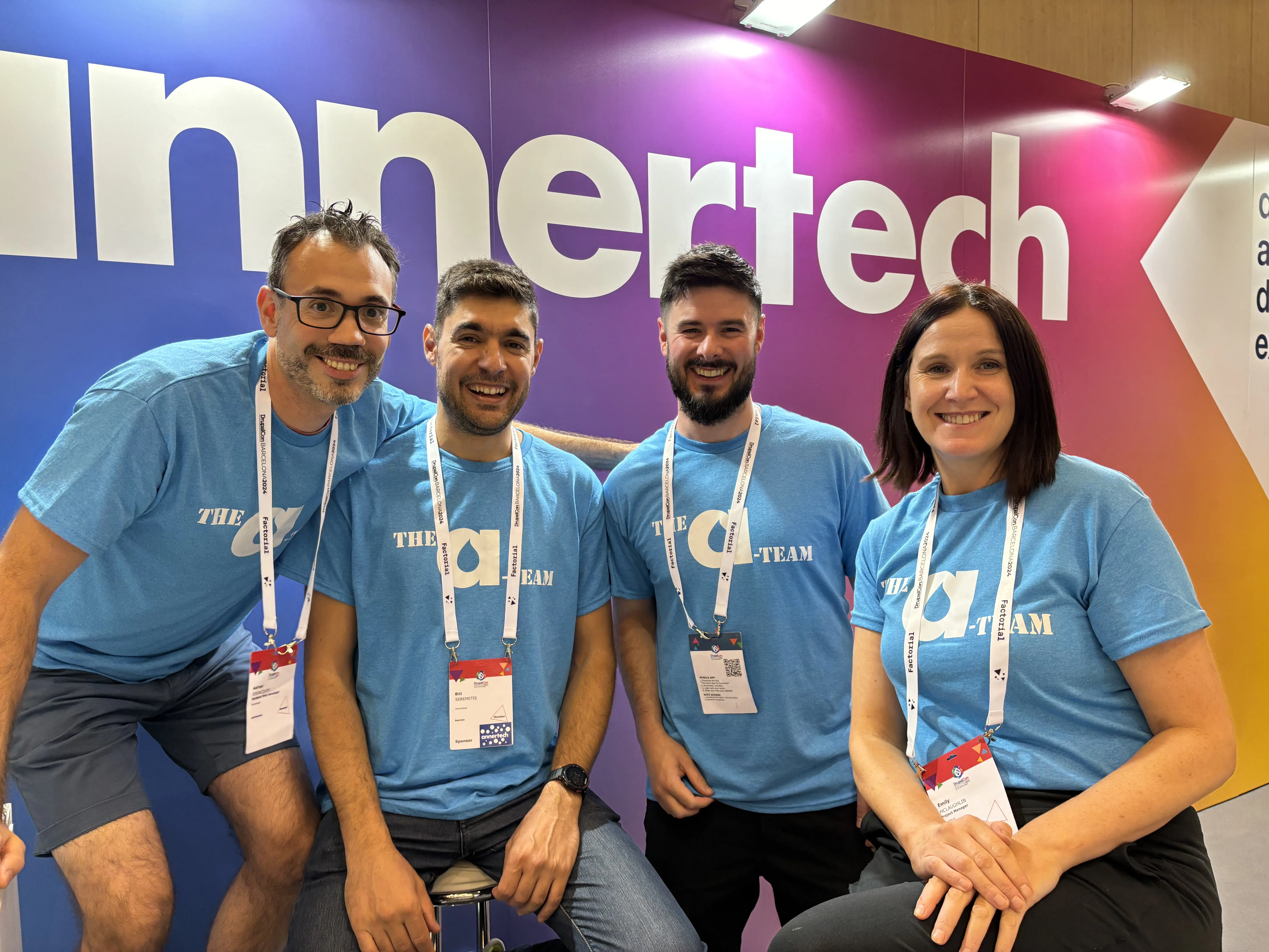 Four Annertech staff members in blue T-shirts that say “The A-Team“ sit in front of the Annertech booth.