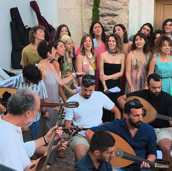 A group of people play lyres, surrounded by others who are appreciating the music
